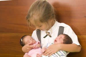Big sister holds newborn twins