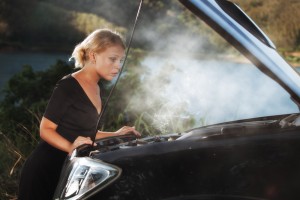Woman looks into engive of smoking car