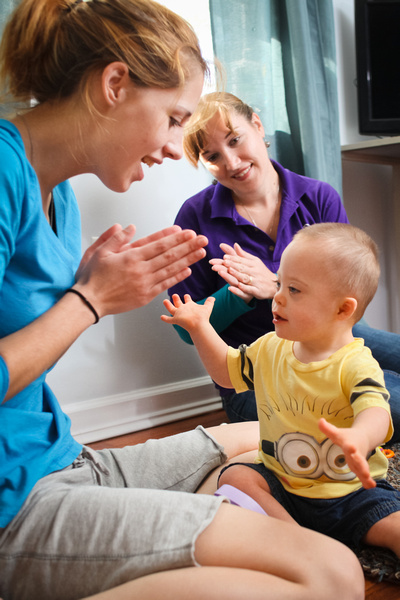 Mother, toddler, and early interventionist clapping while playing on the floor.